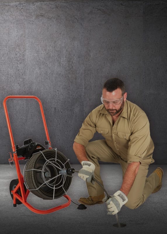 Plumber Performing Rooting Services on Cement Floor